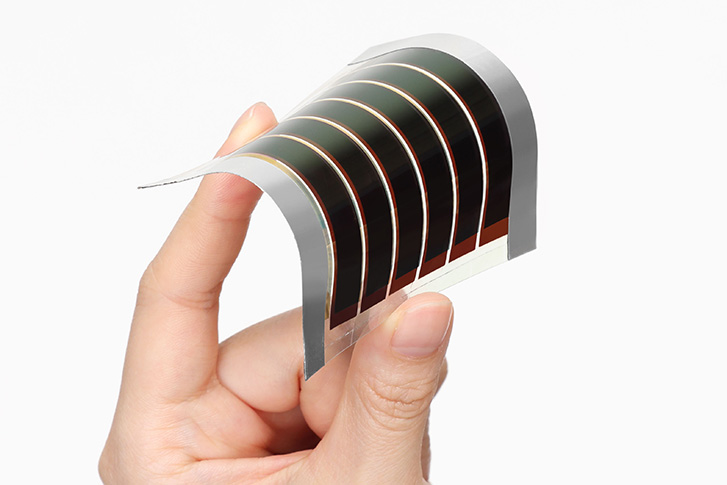 An image showing a perovskite solar cell bent by hand, highlighting its thinness, light weight, and flexibility